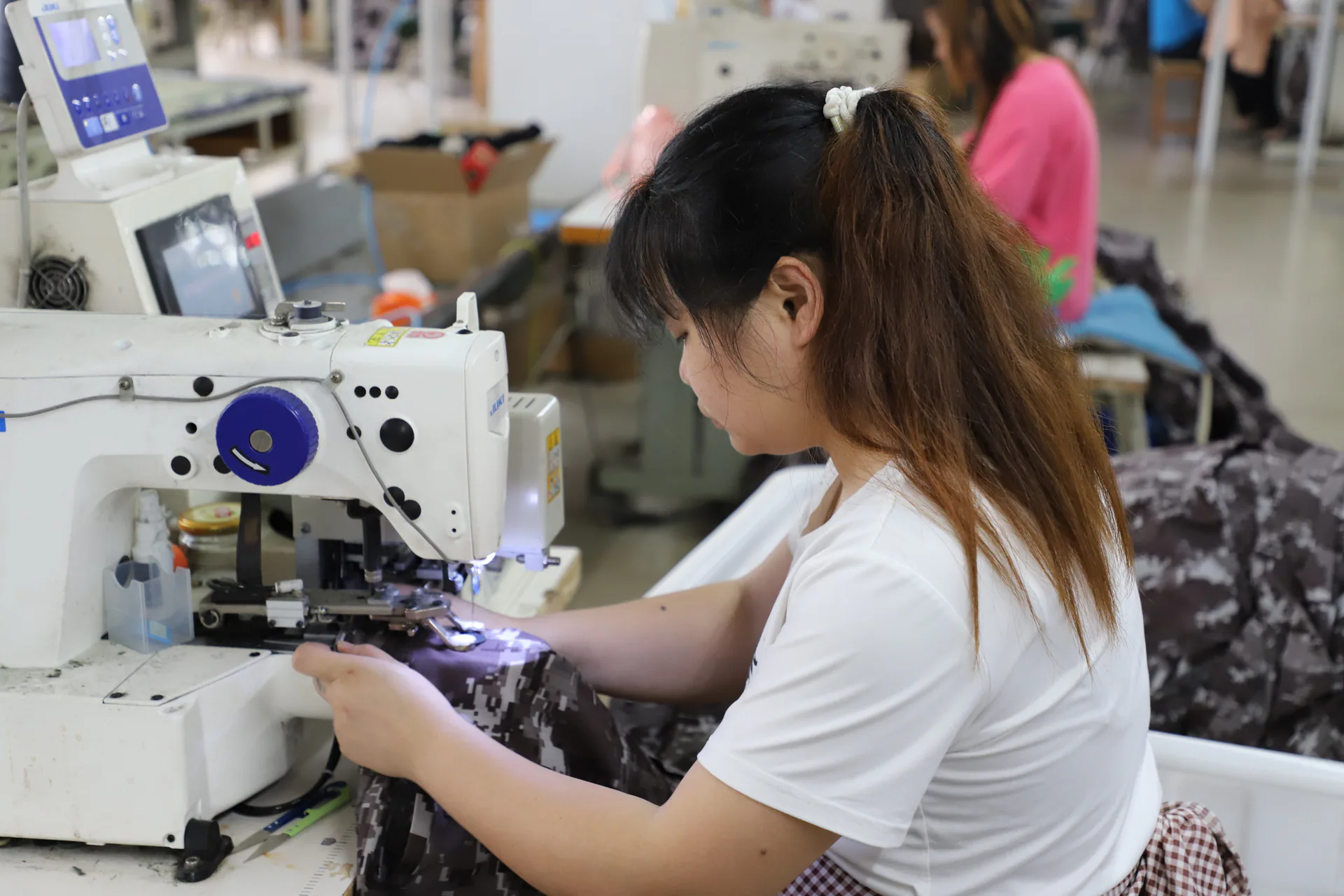 Worker operating an industrial sewing machine in a Wuhan Jinteng production area